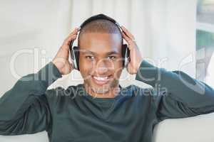 Smiling man with headphones on the sofa