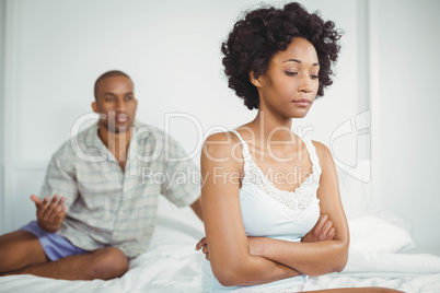 Upset woman sitting on bed after argument