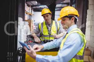 Warehouse worker talking with forklift driver
