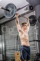Shirtless man lifting barbell
