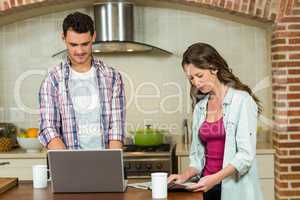 Man using laptop and woman reading newspaper