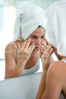 woman in a hair towel inspecting her complexion