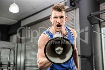 Muscular trainer shouting on megaphone