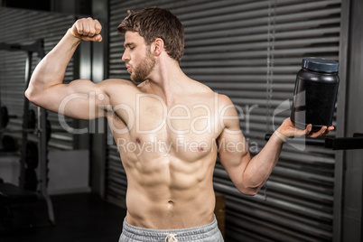 Shirtless man showing biceps and holding can