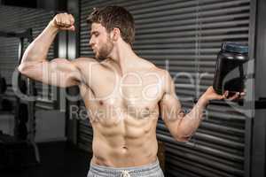 Shirtless man showing biceps and holding can
