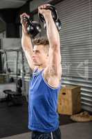 Muscular man lifting heavy kettlebells