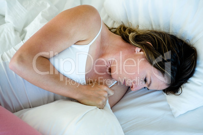 sick woman lying in bed looking unwell