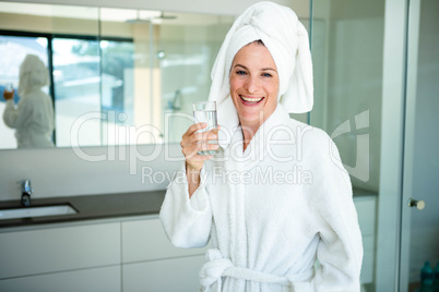 woman in a dressing gown drinking a glass of water