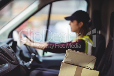 Delivery driver driving van with parcels on seat
