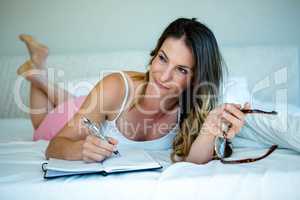 smiling woman with glasses writing in a book