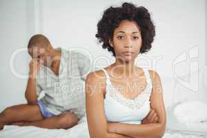 Upset woman sitting on bed after argument
