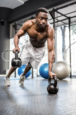 Muscular man doing push up with kettlebells