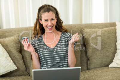 Excited young woman shopping online with a credit card