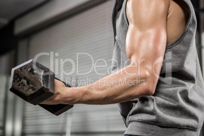 Muscular man with grey jumper lifting dumbbell