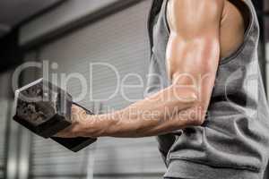 Muscular man with grey jumper lifting dumbbell