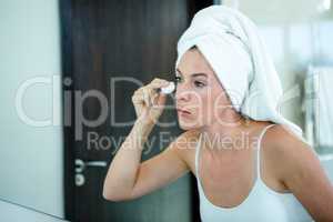 woman cleaning her skin in front of the mirror