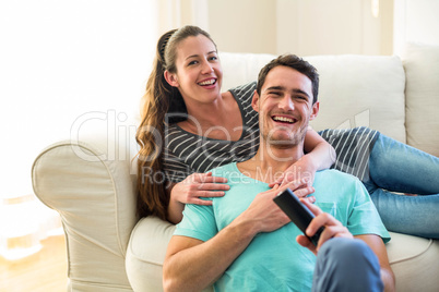 Happy young couple watching television together on sofa