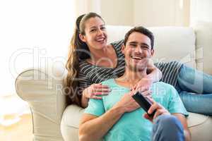 Happy young couple watching television together on sofa