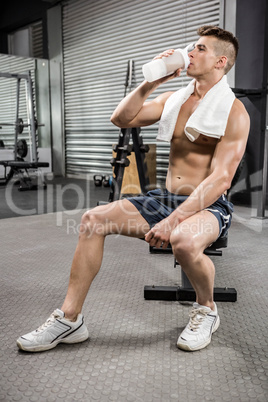 Shirtless man on bench drinking protein shake