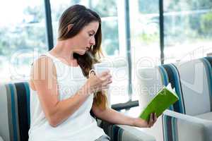 woman drinking coffee and reading a book