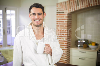 Portrait of young man in bathrobe holding a cup of tea