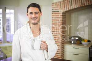 Portrait of young man in bathrobe holding a cup of tea