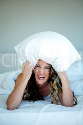 playful woman covering her head with a pillow