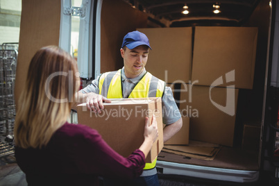 Delivery driver handing parcel to customer outside van