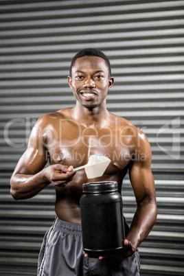 Shirtless man holding protein powder