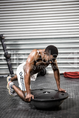 Muscular man doing push up on bosu ball