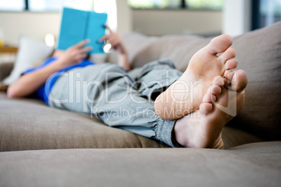 woman lying on the couch reading a book