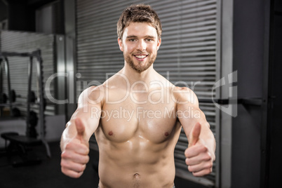 Smiling shirtless man showing thumbs up