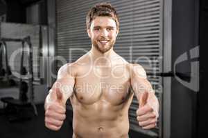 Smiling shirtless man showing thumbs up