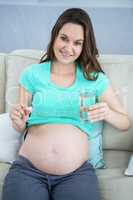 Pregnant woman holding glass of water and pills
