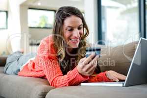 smiling woman lying on the couch on her laptop
