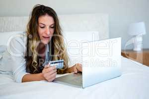 woman lying on her bed on her laptop