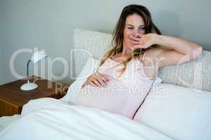 tired pregnant womanlying  in bed yawning