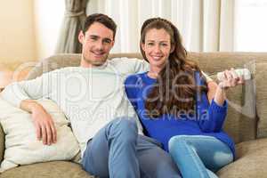 Portrait of young couple watching television together on sofa