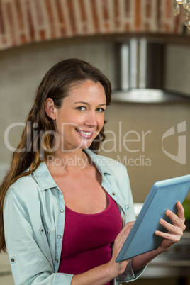 Portrait of woman using tablet in kitchen