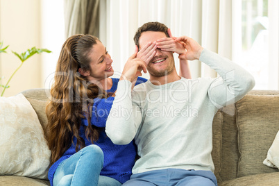 Woman covering mans eyes at home