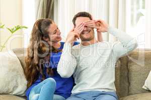 Woman covering mans eyes at home