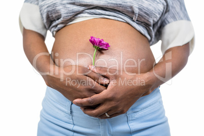 Pregnant woman with flower touching her belly