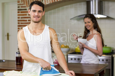 Portrait of man ironing a shirt in kitchen