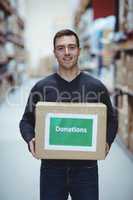 Volunteer smiling at camera holding donations box