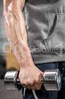 Muscular man with grey jumper holding dumbbell