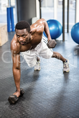 Muscular man doing push up with dumbbells