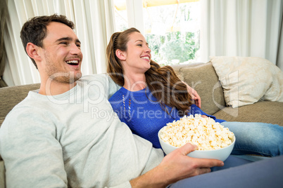 Young couple having popcorn while watching television