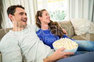 Young couple having popcorn while watching television