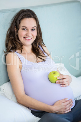 Pregnant woman holding an apple on her bump