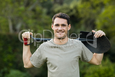 Portrait of young man standing with a gardening shovel